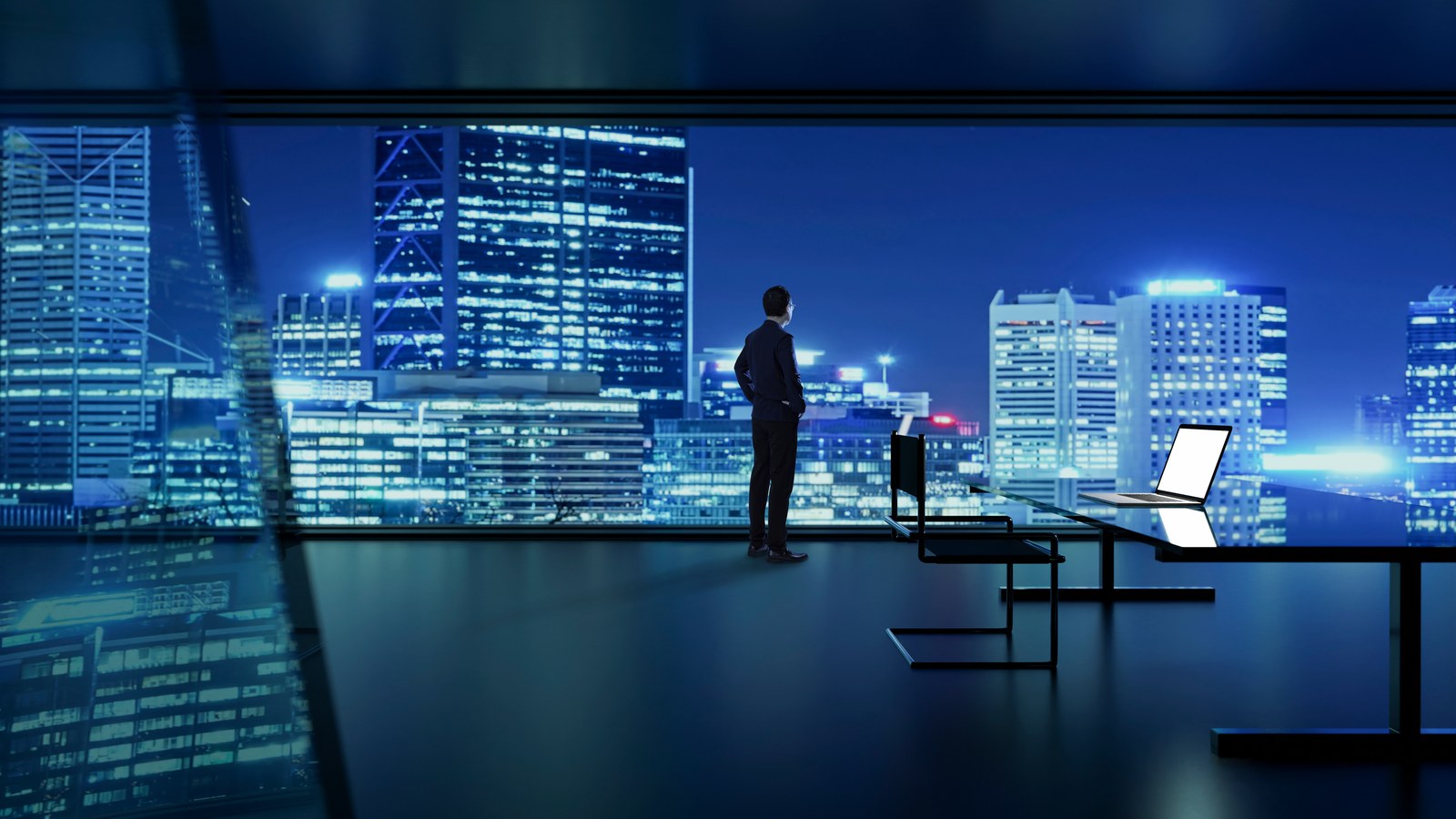 Two RegLeg professionals reviewing a live regulatory compliance dashboard on a desktop monitor in a boardroom, navy and teal lighting.